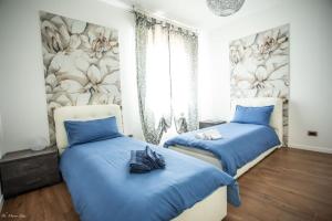 2 camas en un dormitorio con sábanas azules y flores en la pared en Casa Bologna Fiera, en Bolonia