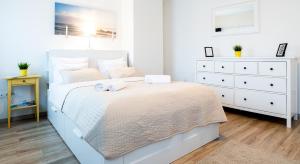 a white bedroom with a large bed and a dresser at Vagabond Corvin in Budapest