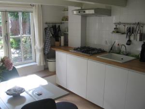 uma cozinha com armários brancos, um lavatório e uma janela em Klavergeluk em Amsterdã