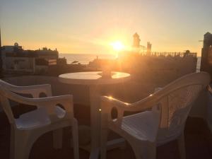 una mesa y sillas con la puesta de sol en el fondo en zazou en Essaouira