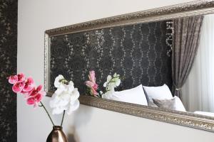 un espejo junto a una cama con flores en un jarrón en Luxury Dream Apartman, en Eger