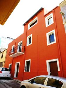 ein orangenes Gebäude mit einem davor geparkt in der Unterkunft Domus Rubra in Castelsardo