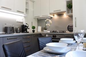 a kitchen with white cabinets and a table with chairs at Luxury Dream Apartman in Eger