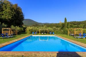 a swimming pool in a yard with blue chairs at Agriturismo Fattoria di Sommaia in Calenzano