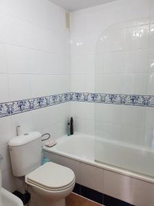 a white bathroom with a toilet and a bath tub at Apartamentos Atlanterra COSTA Y SOL in Zahara de los Atunes