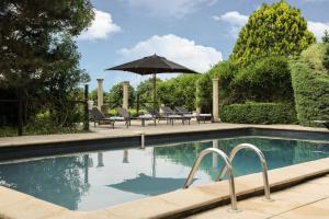 - une piscine avec des chaises et un parasol dans l'établissement Château Les Merles et ses Villas, à Mouleydier