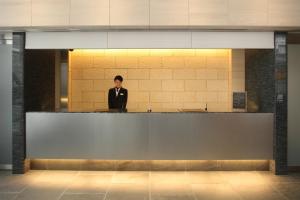 a man in a suit standing behind a counter at Tokyu Stay Kamata - Tokyo Haneda in Tokyo