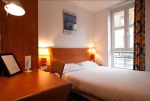 a hotel room with a bed and a desk and window at Hotel Le 21ème in Strasbourg