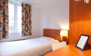 a bedroom with a bed and a desk and a window at Hotel Le 21ème in Strasbourg