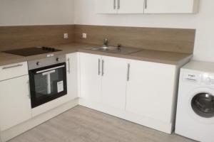 eine Küche mit weißen Schränken, einer Spüle und einem Geschirrspüler in der Unterkunft CHE F3 gauche Terrasse jardin barbecue hypercentre wifi in Cherbourg en Cotentin