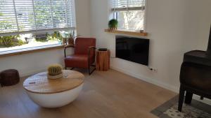 een woonkamer met een tv en een tafel en een stoel bij Prachtige woning aan de duinen in Den Helder