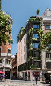 un edificio alto con plantas a su lado en The Garden Suites, en Madrid