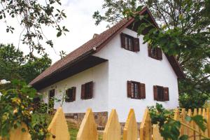 Biały dom z brązowymi oknami i ogrodzeniem w obiekcie Hiša na Pohorju w mieście Šmartno na Pohorju