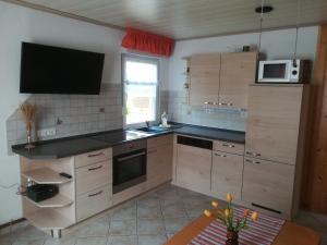 eine Küche mit Holzschränken und einer schwarzen Arbeitsplatte in der Unterkunft Spreewaldhäuser Golinski mit Kamin und umzäutem Grundstück am Neuendorfer See in Alt Schadow