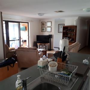 a kitchen and living room with a dish rack on the counter at Comfortable Secure Homeshare in Perth