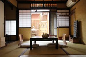 een kamer met een tafel en stoelen in een kamer met ramen bij Bed & Breakfast Tsukiya in Kyoto