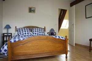 Le Petit Mingot في Druy-Parigny: غرفة نوم بسرير خشبي مع وسائد زرقاء وبيضاء