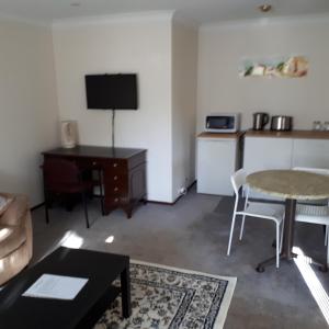 a living room with a table and a desk with a tv at Comfortable Secure Homeshare in Perth