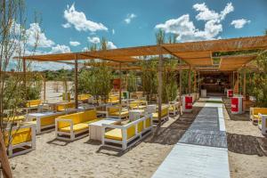 a restaurant with yellow chairs and tables in the sand at MariSole in Constanţa