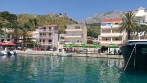 un bateau dans l'eau à côté de certains bâtiments dans l'établissement Apartments Gaston, à Podgora