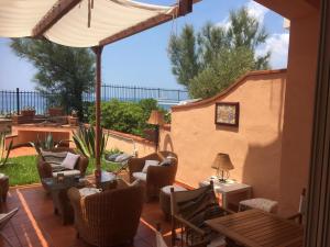eine Terrasse mit Stühlen, Tischen und einem Sonnenschirm in der Unterkunft Il terrazzino di Lulù in Cetraro