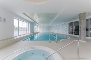 a large swimming pool with a tub in a room at Zefiro Chmielna in Gdańsk