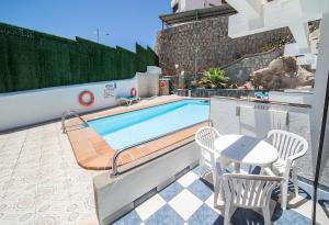uma piscina com uma mesa e cadeiras num pátio em Apartamentos Monte Verde em Puerto Rico de Gran Canaria