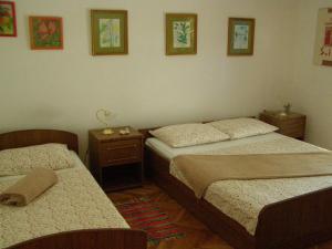 2 camas en una habitación con 2 mesas y cuadros en la pared en House Kaić, en Selce