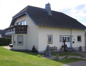 a white house with a black roof at Ferienwohnung Haus Andre _ fuer 4 in Ulmen