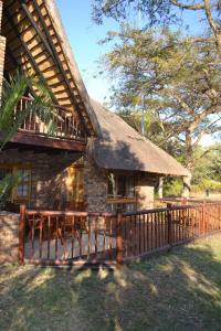 a house with a thatched roof and a wooden fence at Kruger Park Lodge - Golf Safari SA in Hazyview