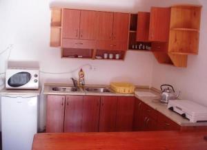 a kitchen with wooden cabinets and a white microwave at Petra Apartmanok in Velem