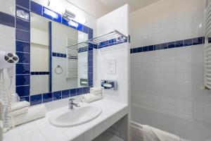 a white bathroom with a sink and a mirror at Thalacap Île de Ré - Thalasso & Spa in Ars-en-Ré