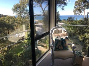 a chair in front of a window looking out at the ocean at Lorne Sea View Terrace house in Lorne