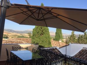 a patio with a table and chairs and an umbrella at Baraka Pensión in Ronda
