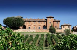 um grande edifício de tijolos com um campo de plantas em Agriturismo Terra Rossa em Valiano