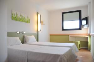 a hotel room with two beds and a window at Ibis Budget Girona Costa Brava in Girona
