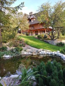 a log home with a pond in front of it at Gorce Oasis in Szlembark