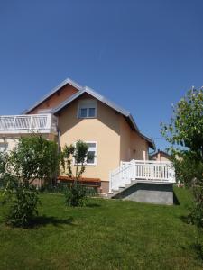 a large house with a white balcony and a yard at Rooms Josip in Korenica