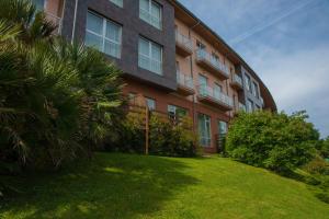 un edificio con una palmera delante de él en Apartamentos Mar Comillas en Comillas