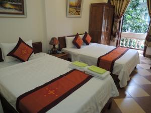 two beds in a hotel room with a window at Hanoi Ecogreen Hostel in Hanoi