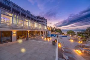 a building with a patio with tables and chairs at Hotel Malin in Malinska