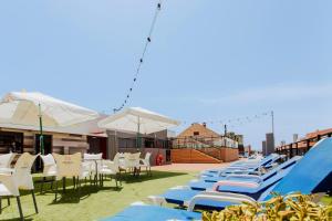 eine Reihe von Liegestühlen und Sonnenschirmen auf einer Terrasse in der Unterkunft Hotel Cuco in Benidorm