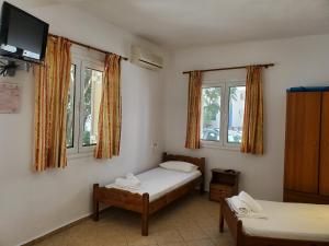 a room with two beds and a flat screen tv at Icthyoessa in Agios Kirykos