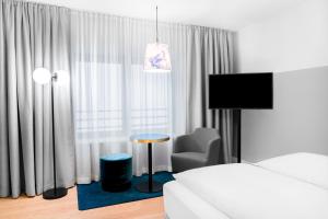 
a living room with a television and a bed at STAGE 12 Hotel by Penz in Innsbruck
