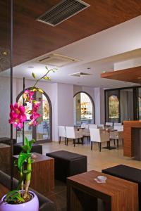 a room with tables and chairs and a vase with pink flowers at Hotel Lipa in Postira