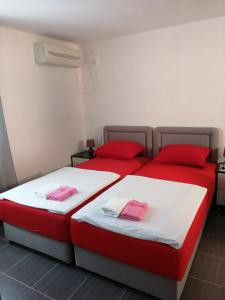 twee bedden in een kamer met rode kussens erop bij Sara apartments in Budva