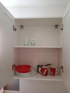 een kast met daarop een rode kom en borden bij Sara apartments in Budva