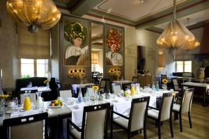 una sala da pranzo con tavoli, sedie e lampadari a braccio di Fletcher Hotel-Restaurant Kasteel Erenstein a Kerkrade