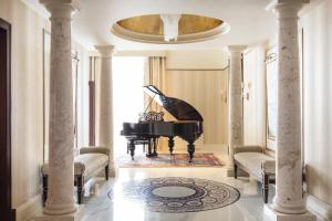 a grand piano in a living room with columns at Grand Hotel Europe, A Belmond Hotel, St Petersburg in Saint Petersburg