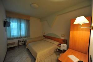 a bedroom with a bed and a table and a lamp at Hotel Il Cammino Di Francesco in Bastia Umbra